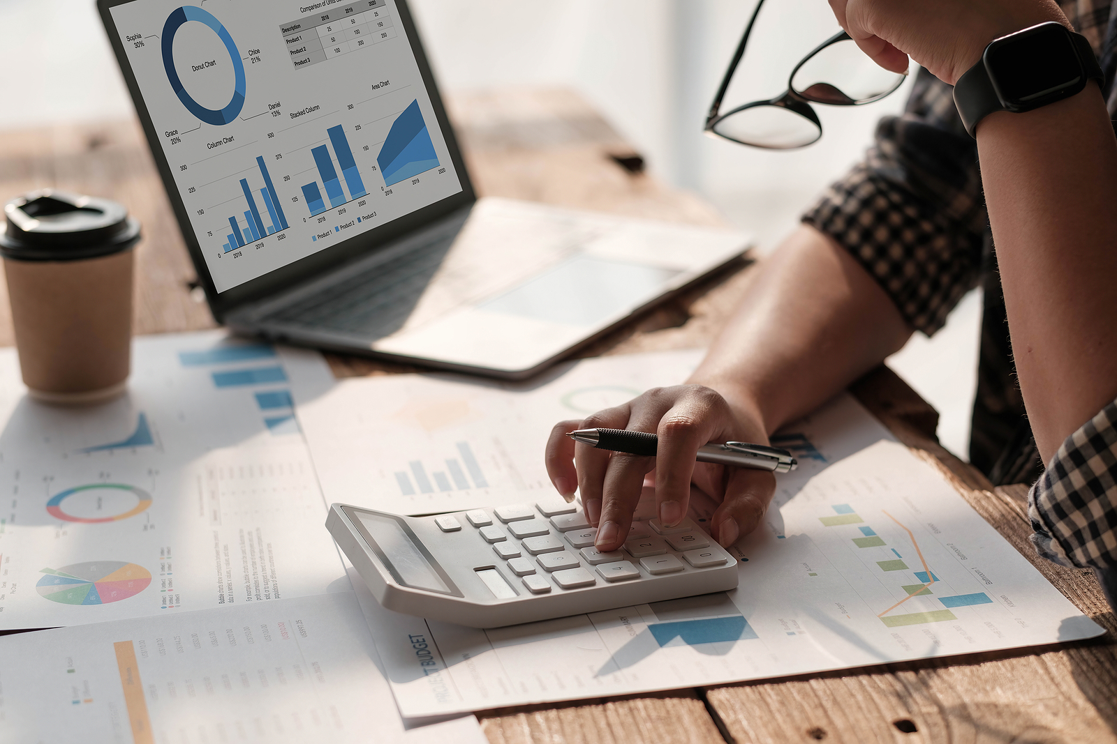 Close up Business woman using calculator and laptop for do math short-term vs. long-term CDs finance on wooden desk in office and business working background, tax, accounting, statistics and analytic research concept.