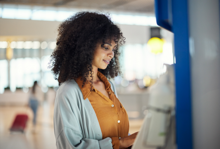 Woman using self service kiosk to use her funds after deciding personal loan vs. personal line of credit