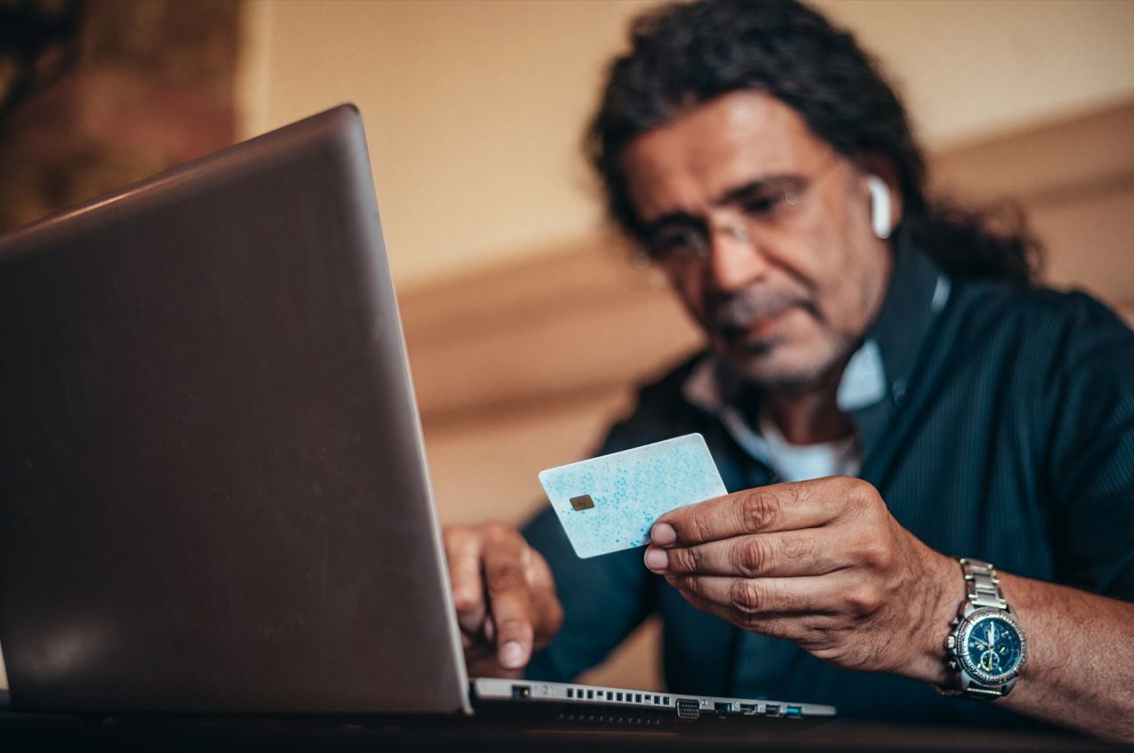 Senior hispanic cuban men using laptop to see how to prevent child identity theft and a credit card while online shopping