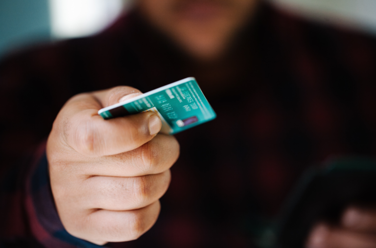 One man handing a credit card for payment in the blurry background