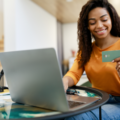 Happy woman holding debit credit card, using pc to learn differences between revolving credit and installment loans