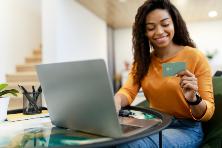 Happy woman holding debit credit card, using pc to learn differences between revolving credit and installment loans